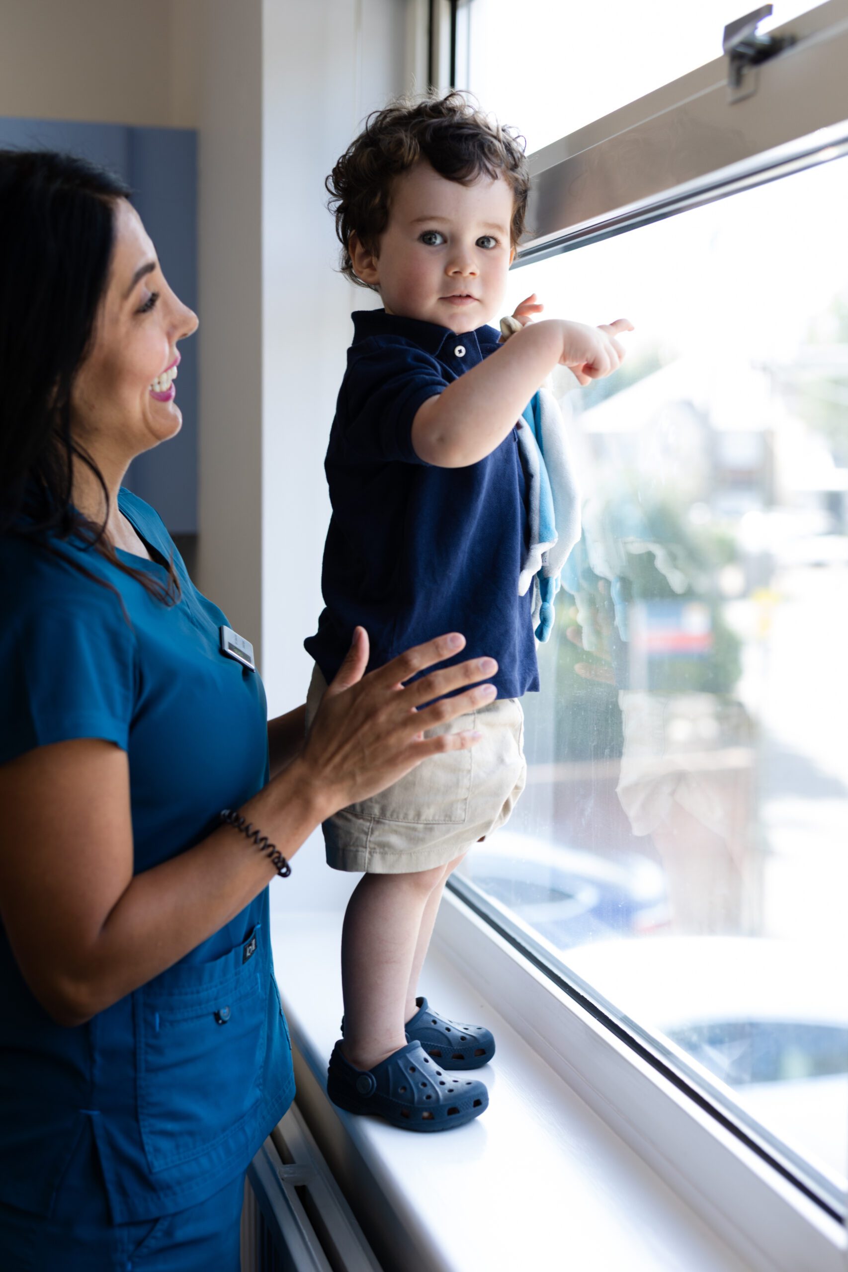 child standing at a window with a female dentist