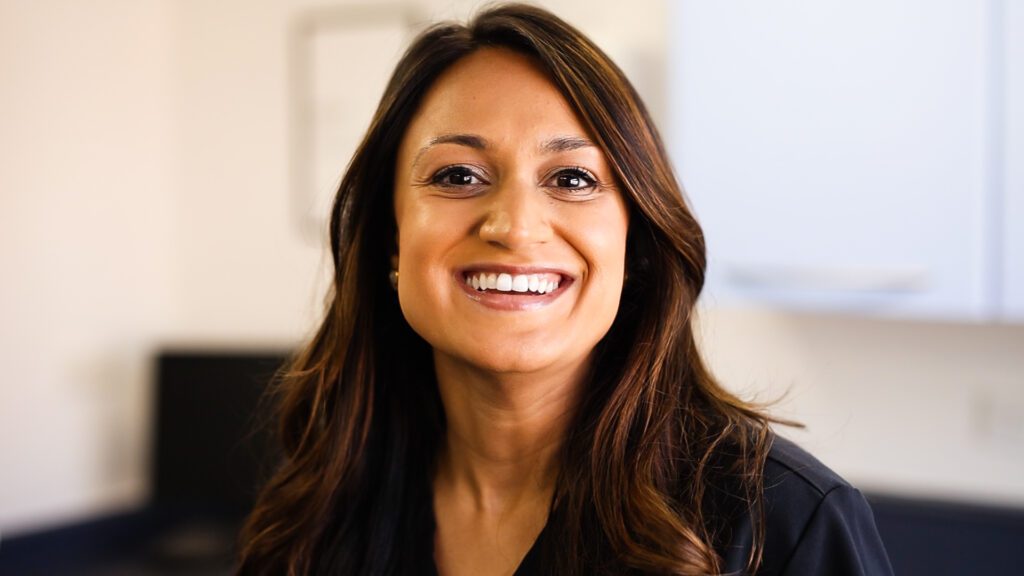 Female dentist smiling at the camera with long brown hair