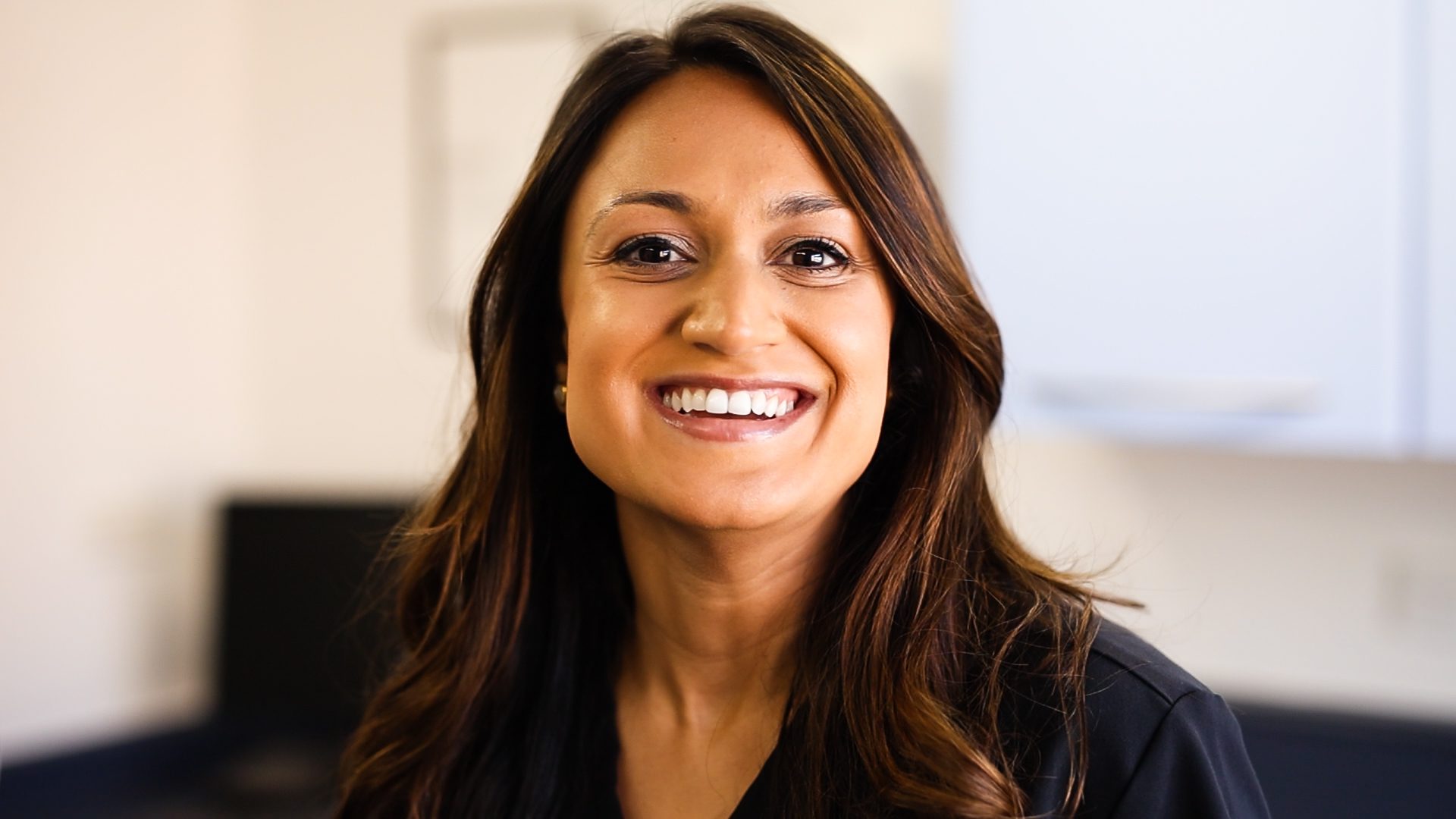 Female dentist smiling at the camera with long brown hair