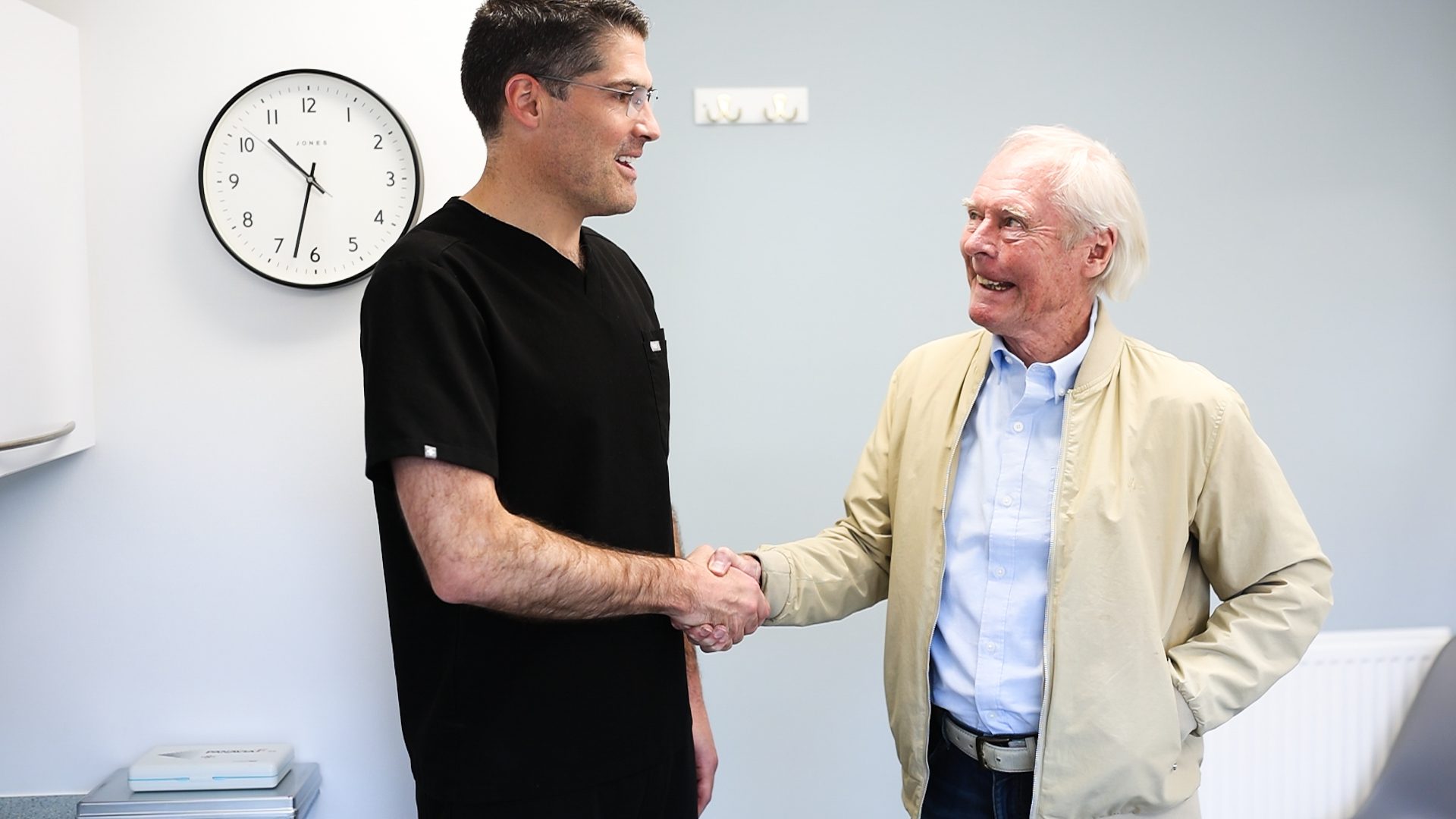 Principle dentist shaking hands with a mature patient