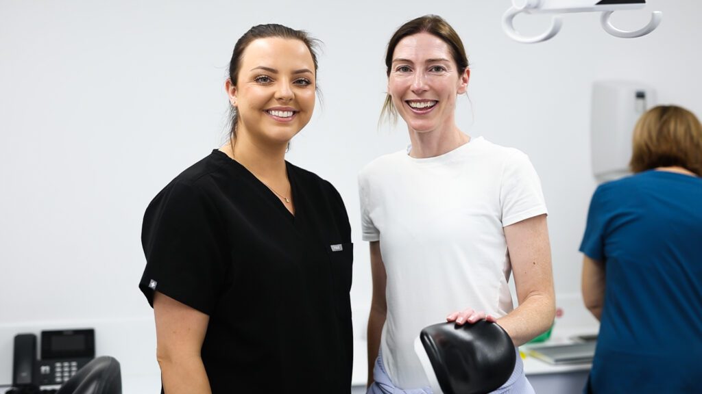 Female dentist and patient standing together smiling at the camera