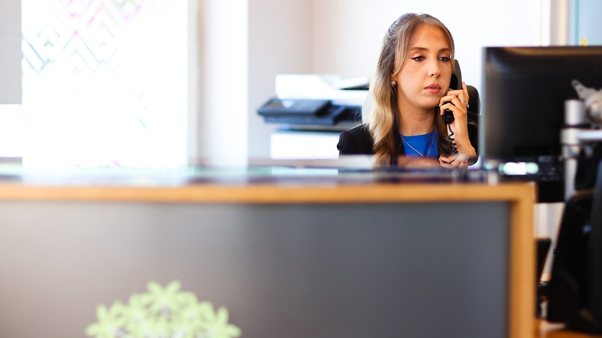 female receptionist on the telephone in front of her computer working